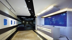 Eine moderne Lobby mit Marmorboden, einer Rezeption und einer Wand mit einer Weltkarte.