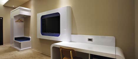 A modern, compact room with a built-in desk, a chair, a TV, and a wardrobe with a hanging rack.