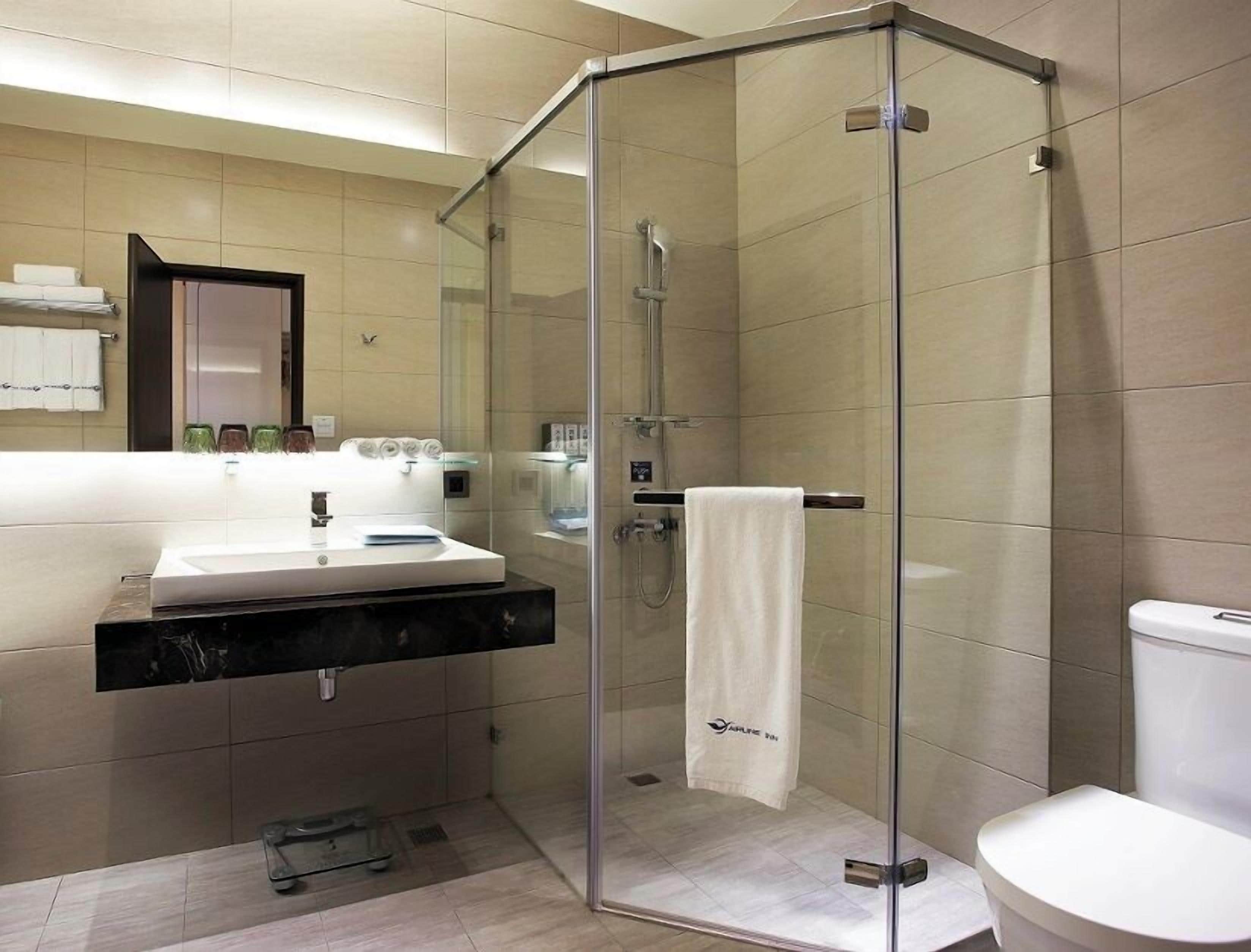 Un baño moderno con ducha envuelta en vidrio, lavamanos con espejo y retrete.