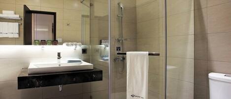 Un baño moderno con ducha envuelta en vidrio, lavamanos con espejo y retrete.
