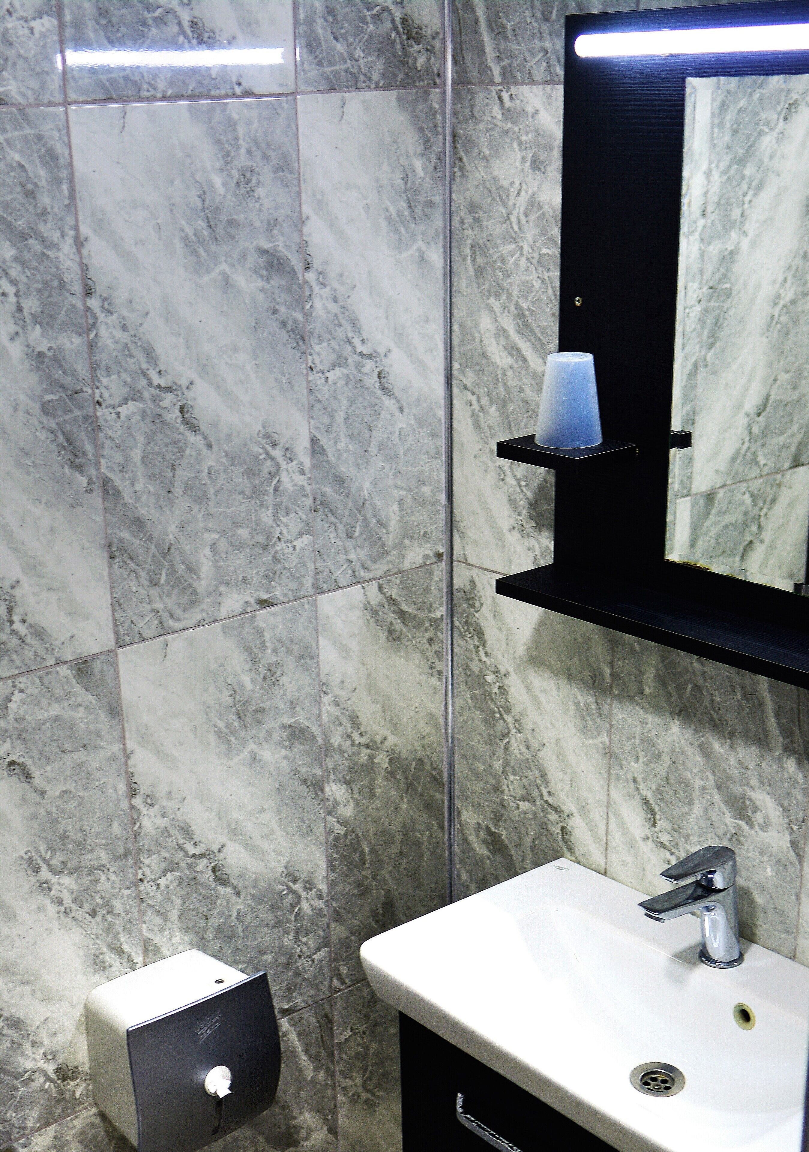 A bathroom with a white sink, a mirror, and a hand dryer.