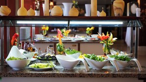 A buffet setup with various bowls of food, including salads and vegetables, and decorative vases on a glass display. - Gumuldur Mavi Deniz Otel (Menderes)