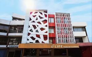 A modern building with a geometric facade, a visible restaurant named 'LIFE PANGLIMA SUDIRMAN' at the ground level, and a clear sky in the background. - Life Hotel Sudirman Surabaya (Surabaya)