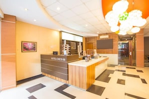 A hotel reception area with a check-in counter, a framed certificate on the wall, and a modern chandelier. - Life Hotel Sudirman Surabaya (Surabaya)