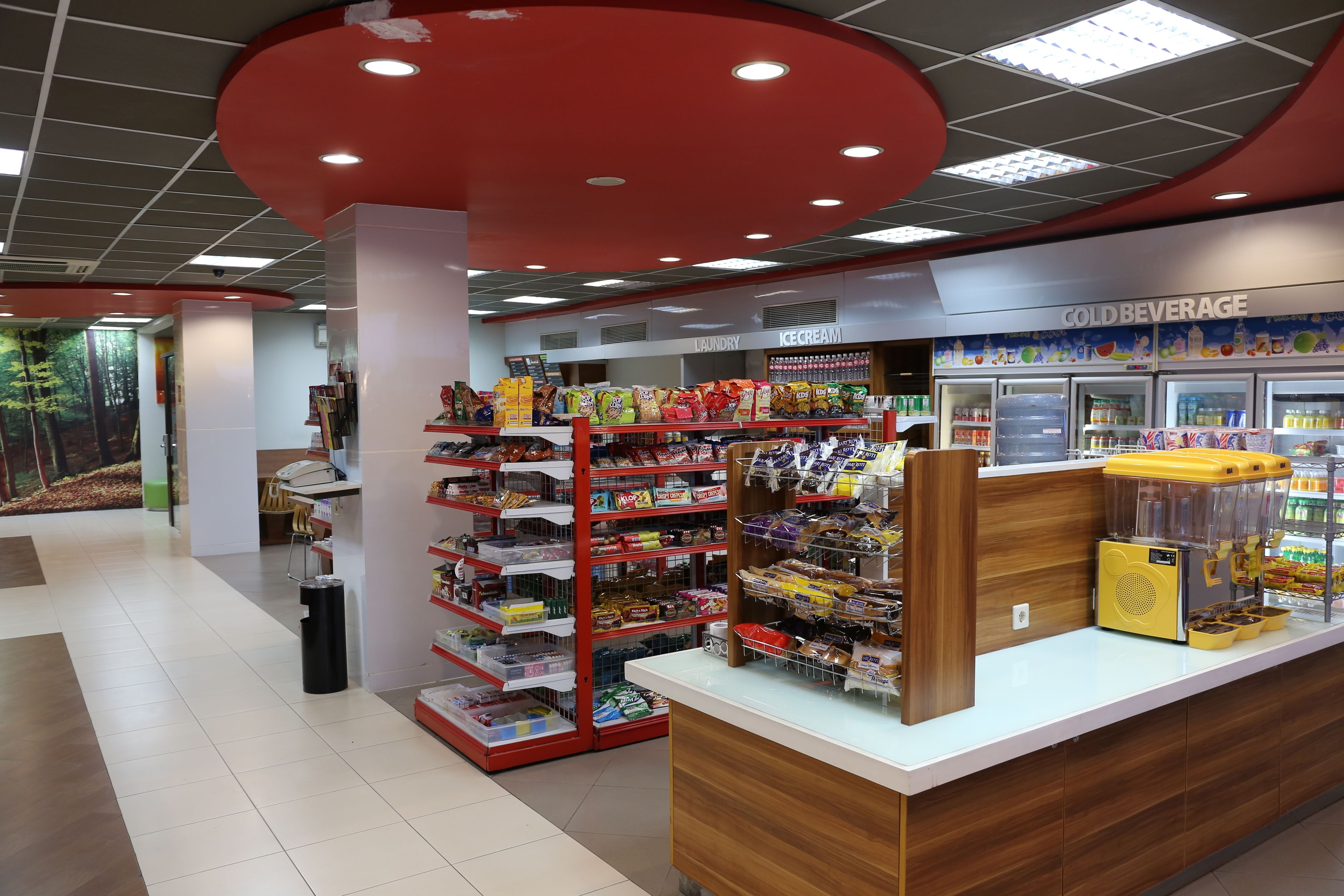 A clean, well-lit store with shelves stocked with snacks and a cold beverage section.