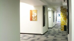 A hotel corridor with a patterned floor, a painting on the wall, and a yellow accent wall at the end. - Citihub Hotel @ Tunjungan (Surabaya)