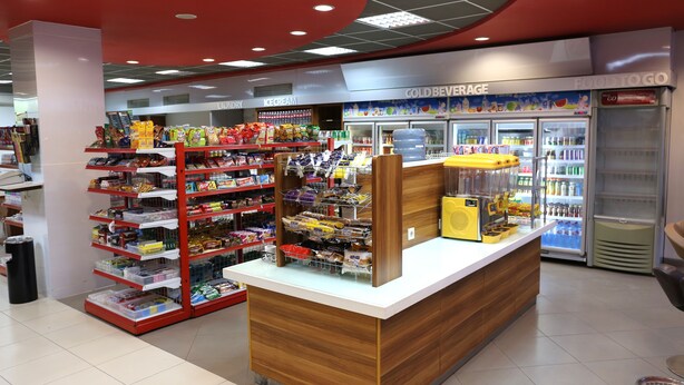 A snack kiosk with a variety of packaged goods and a cold beverage section in a brightly lit store. - Citihub Hotel @ Tunjungan (Surabaya)