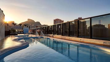 Una piscina al aire libre, sombrillas, sillones reclinables de piscina