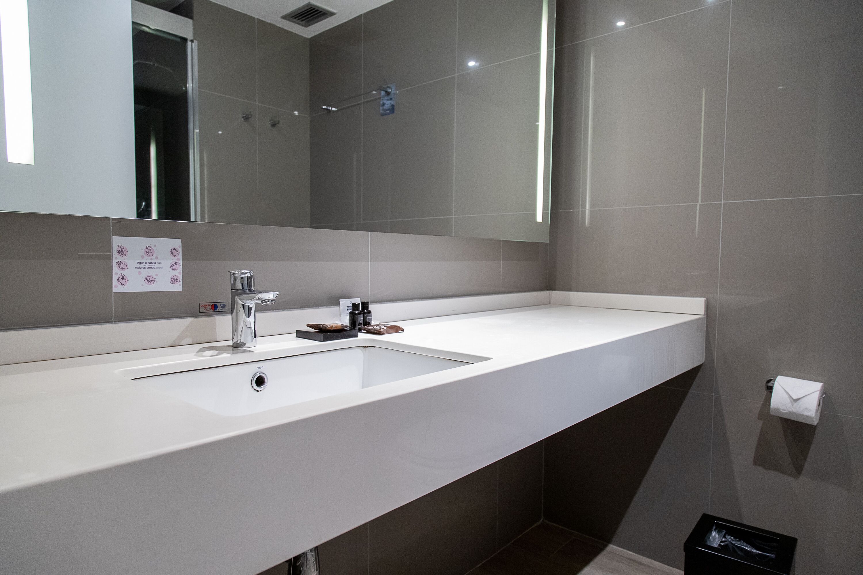 A modern bathroom with a large mirror, a sink, and a shower area.
