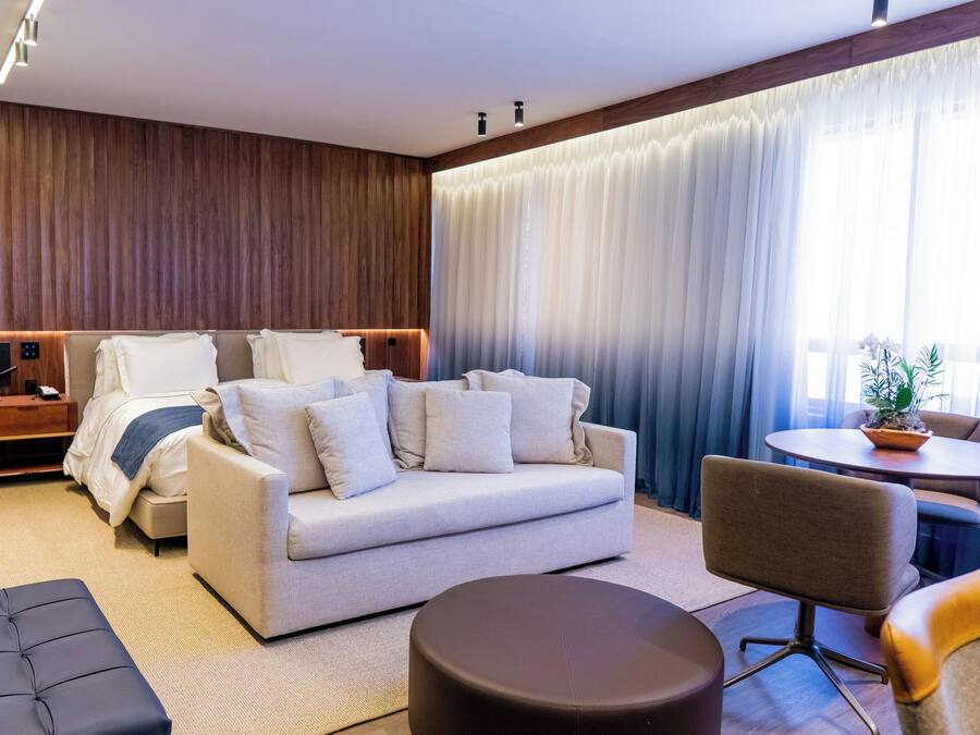 Een moderne hotelkamer met een bed, een slaapbank, een ronde tafel en een stoel.