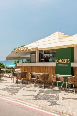 An outdoor seating area with wicker furniture and a view of the ocean. - Radisson Barra Rio De Janeiro (Rio de Janeiro)