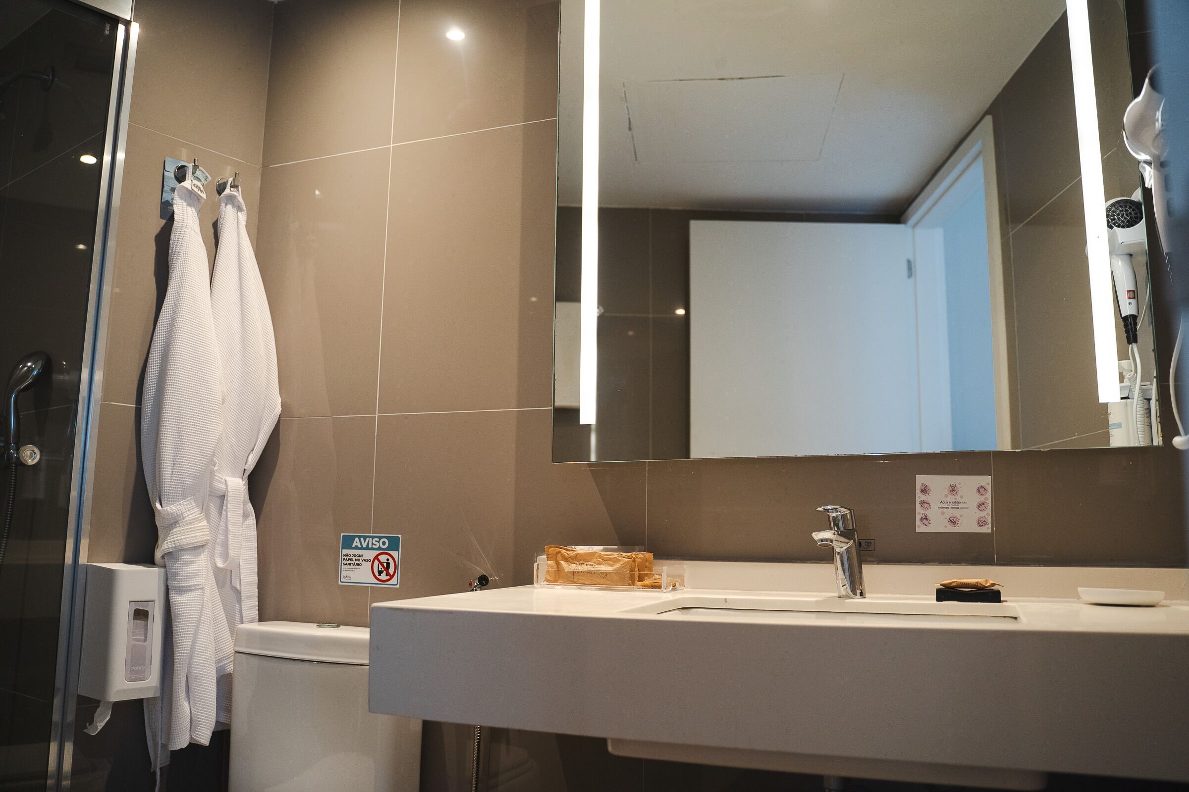 Une salle de bain avec un lavabo blanc, un miroir et une cabine de douche en verre.