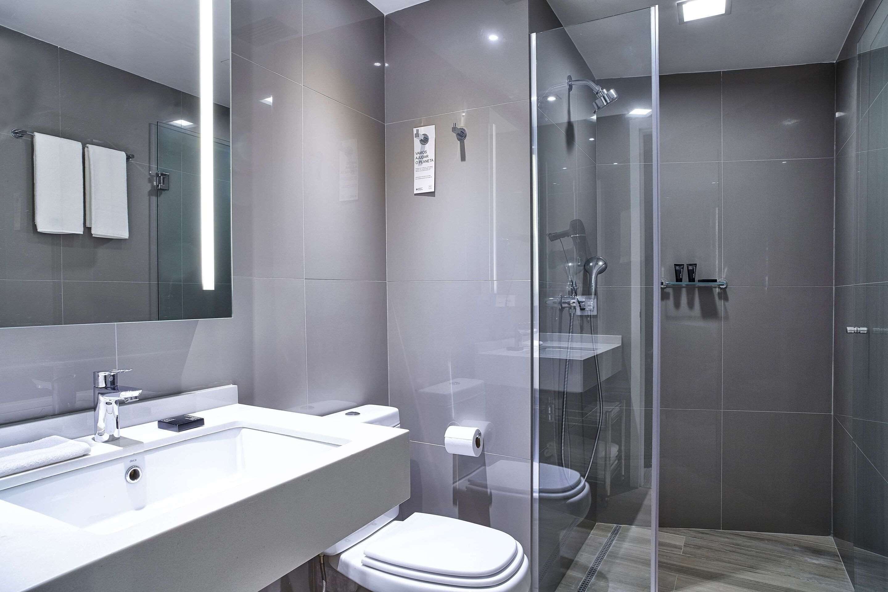 A modern bathroom with a glass-enclosed shower, a white sink, and a toilet.