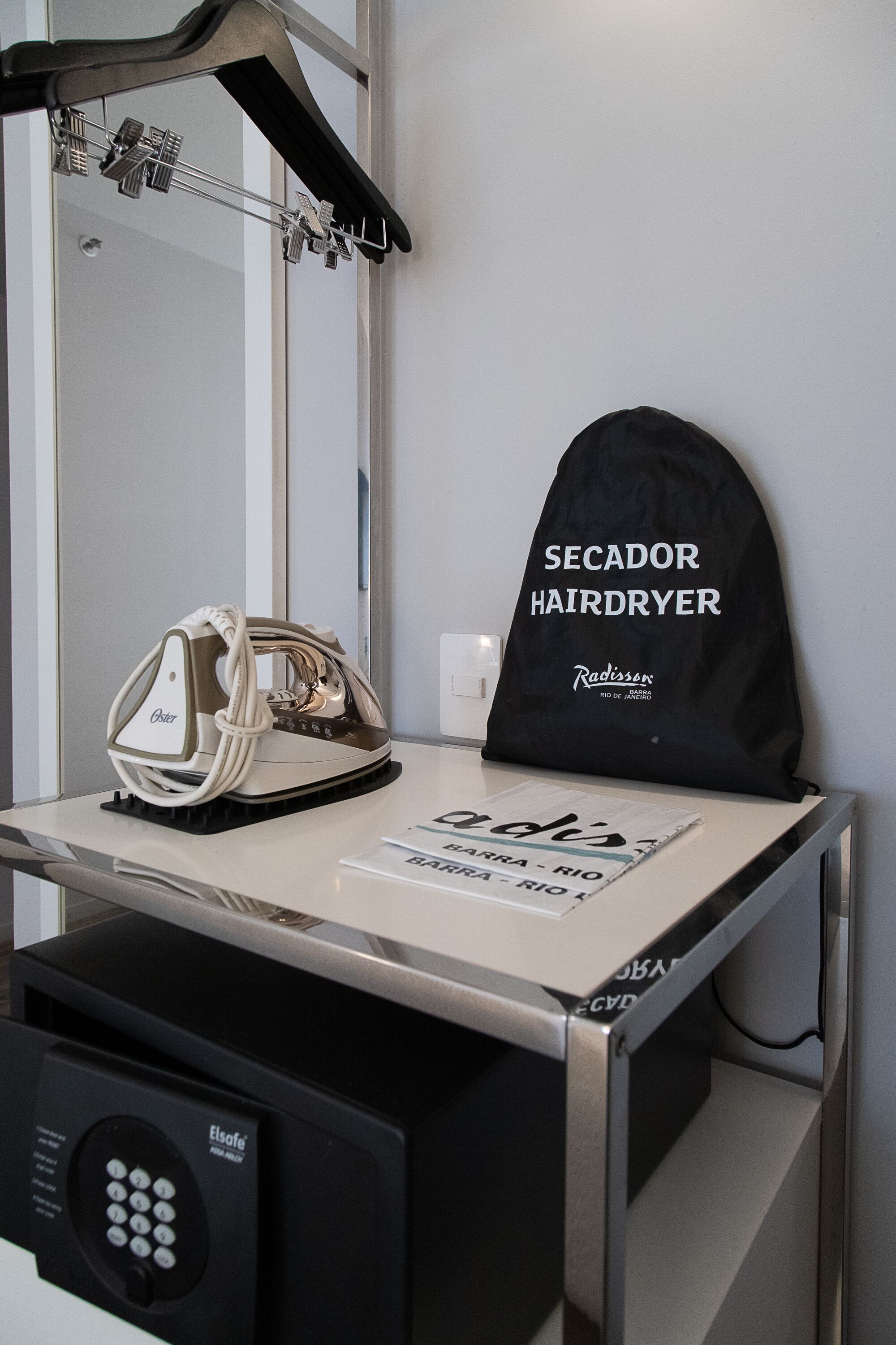 A hairdryer and a bag labeled "Secador Hairdryer" on a counter.