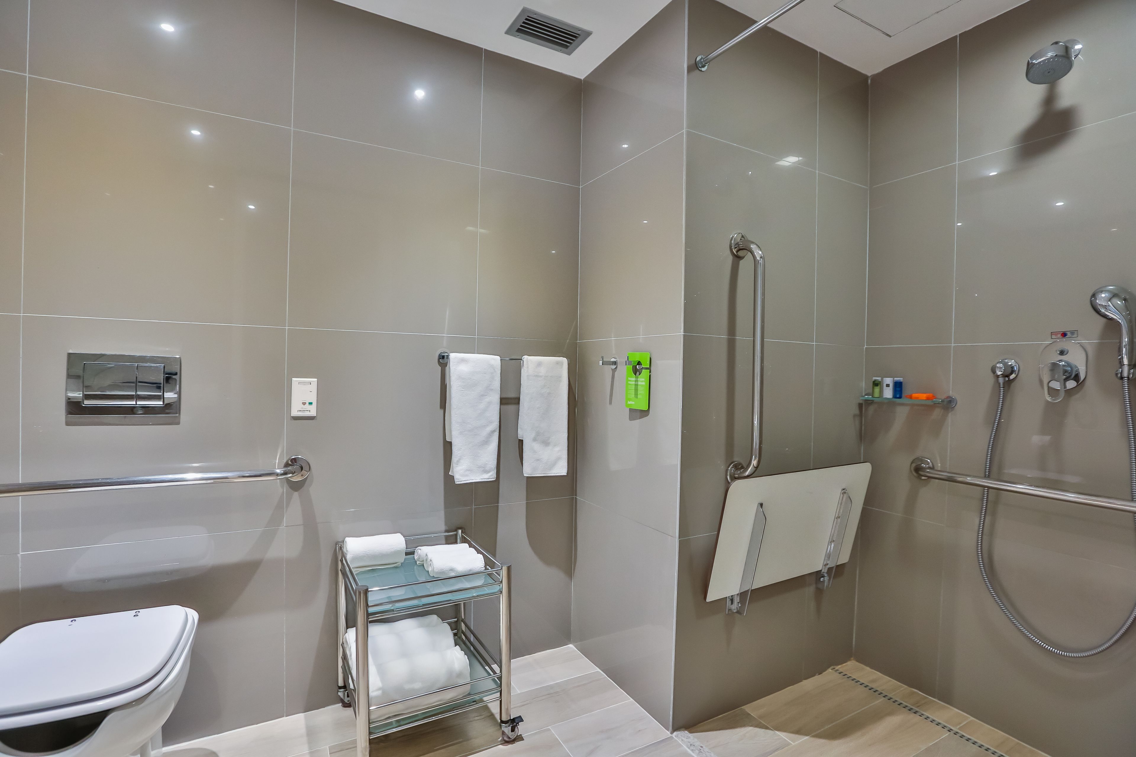 Un baño moderno con cabina de ducha de vidrio, inodoro y repisa de vidrio con toallas.