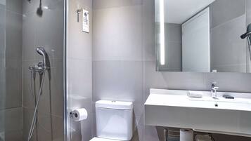 A modern bathroom with a glass shower enclosure, a white toilet, and a sink with a mirror above it.