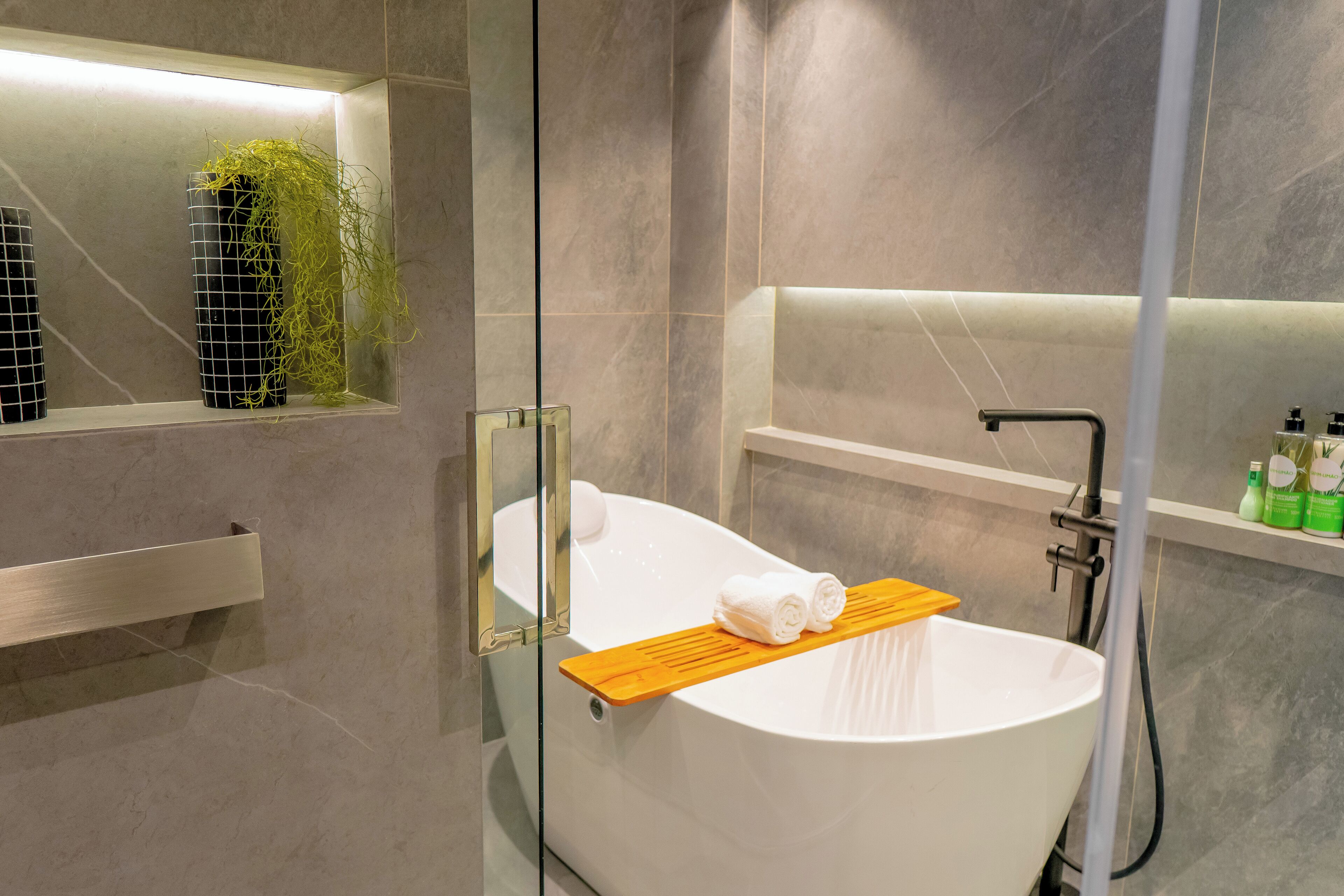 Une salle de bain moderne avec une baignoire sur pieds, une douche à parois de verre et une étagère contenant des articles de toilette.