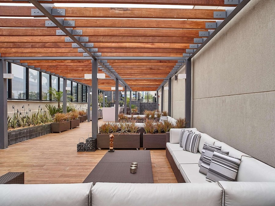 A rooftop terrace with a wooden pergola, outdoor seating, and potted plants.