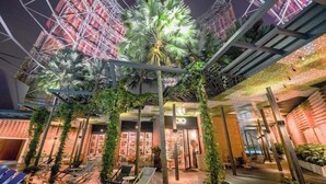 A modern indoor atrium with a central palm tree, surrounded by lounge chairs and a glass ceiling. - Oasia Hotel Downtown Singapore by Far East Hospitality (Singapore)