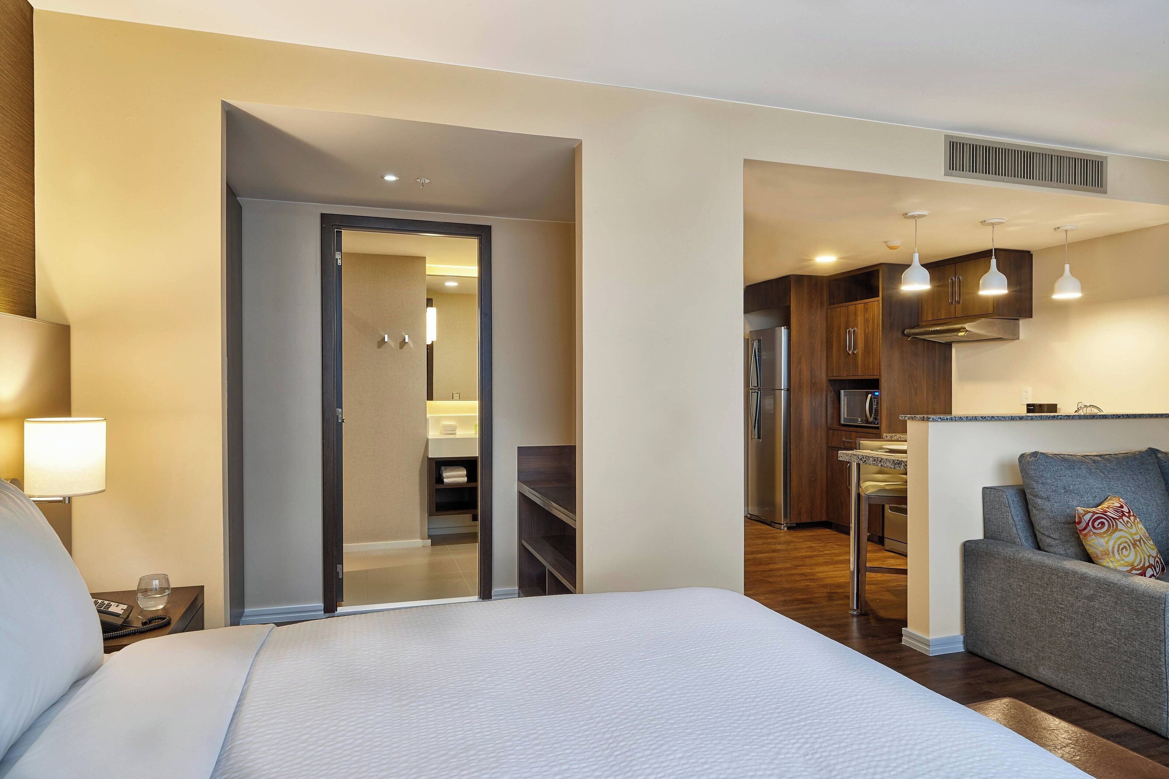 Een hotelkamer met een bed, een bank, een bureau en een kitchenette.