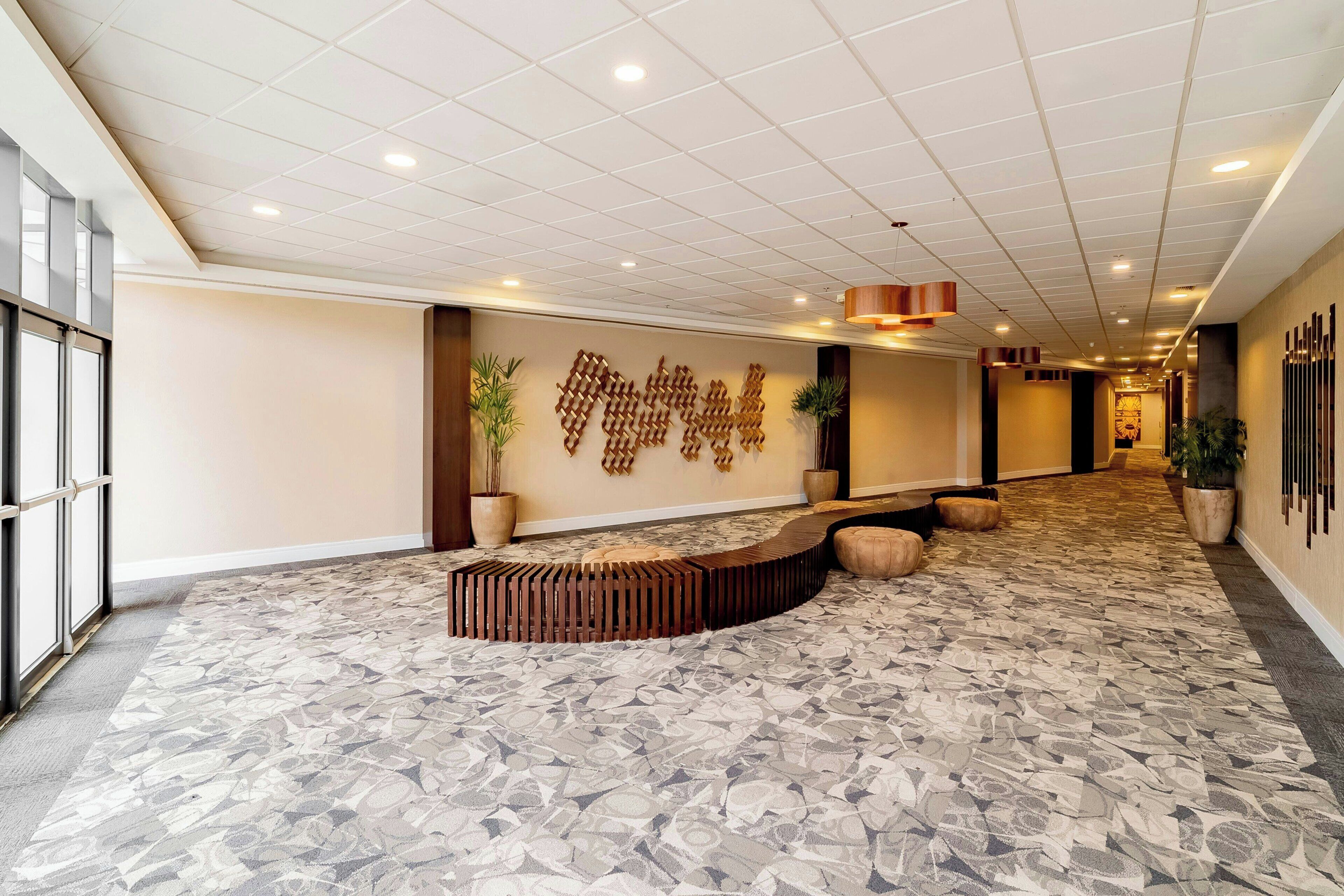 Um hall de hotel moderno com piso estampado, uma instalação artística original na parede e uma área de estar.