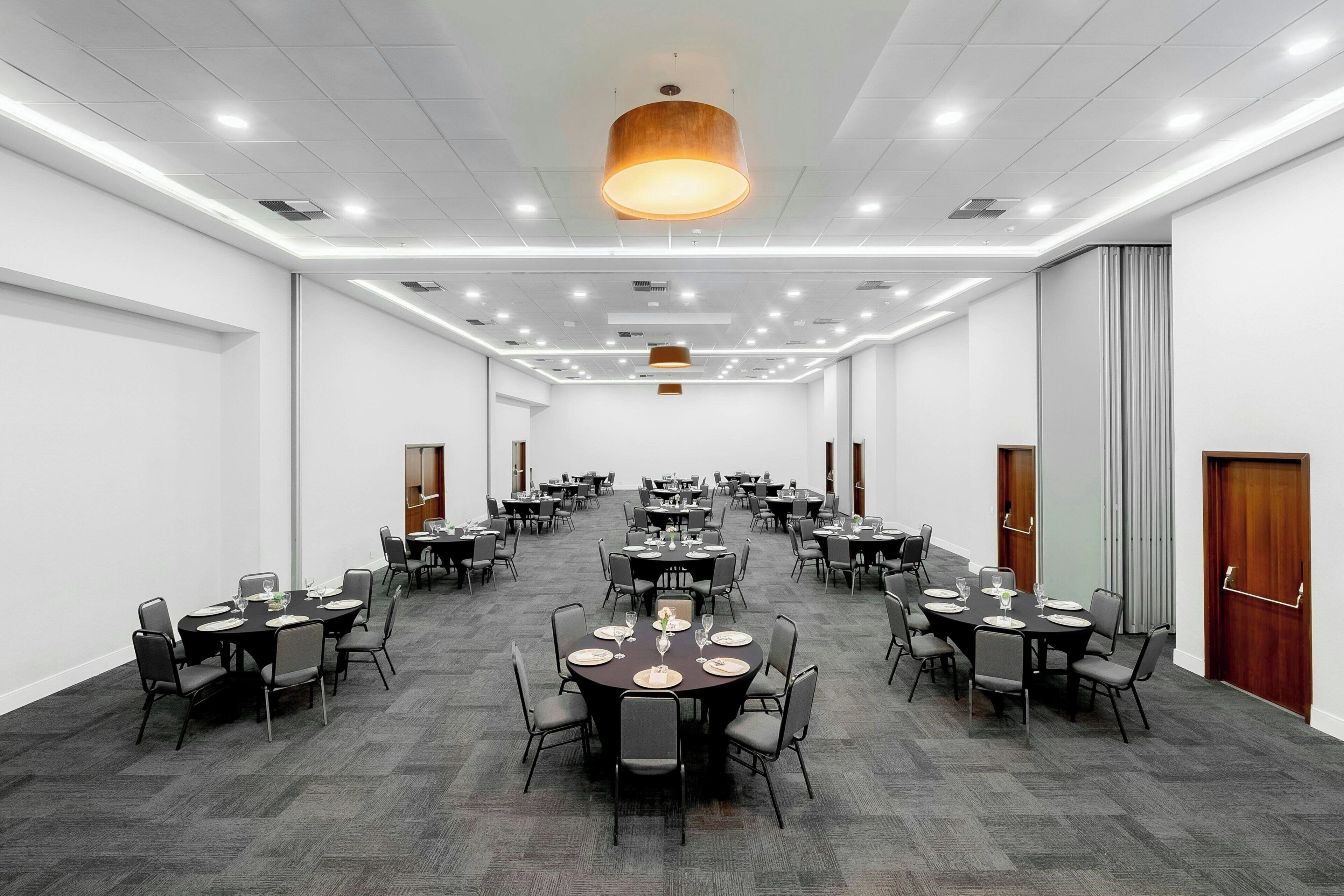 A large conference room with multiple tables and chairs, a modern ceiling design, and a neutral color scheme.