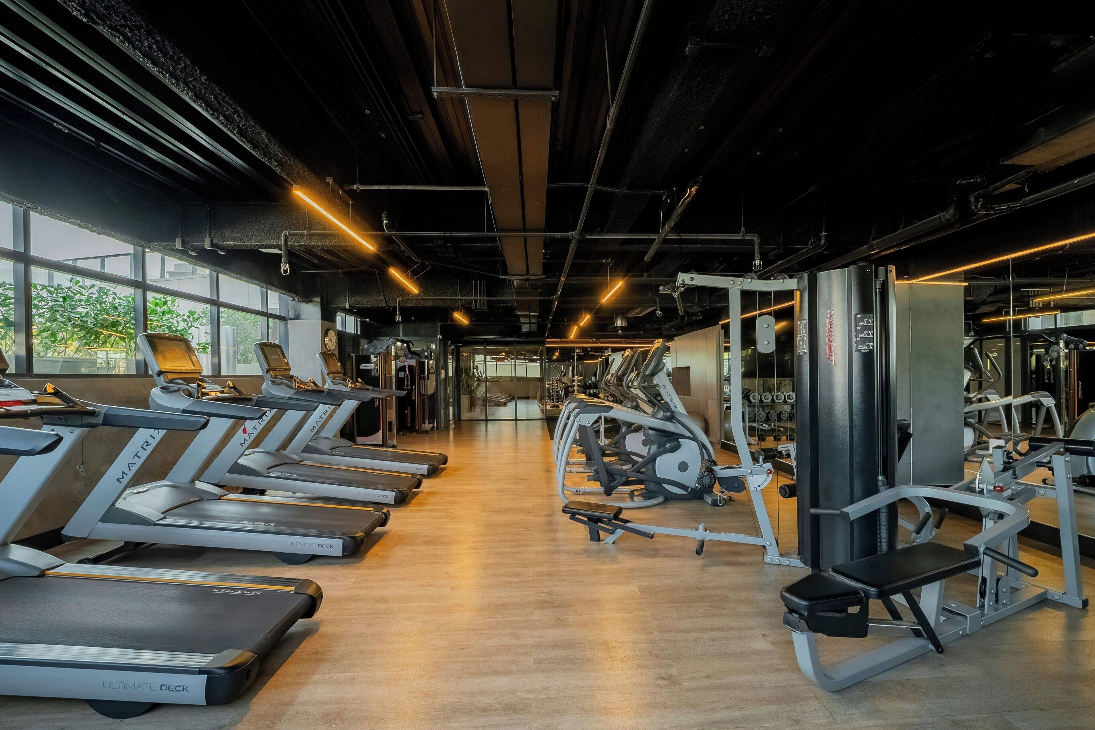 Una palestra con tapis roulant, macchinari per pesi e una parete con specchi.