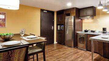 A modern kitchen with dark wooden cabinets, stainless steel appliances, and a dining area with a table set for two.