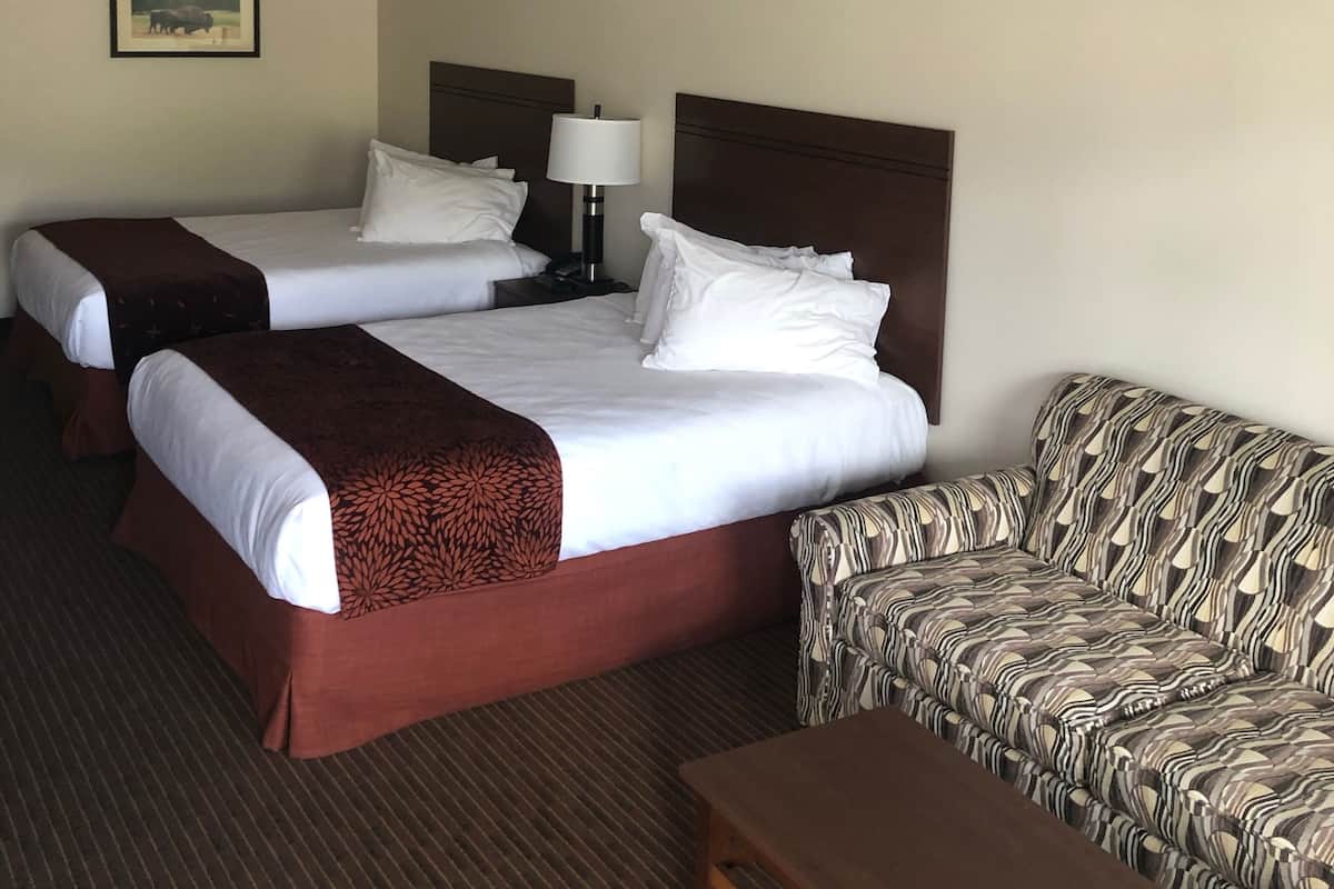 Una habitación de hotel con dos camas, un sofá y una mesita.