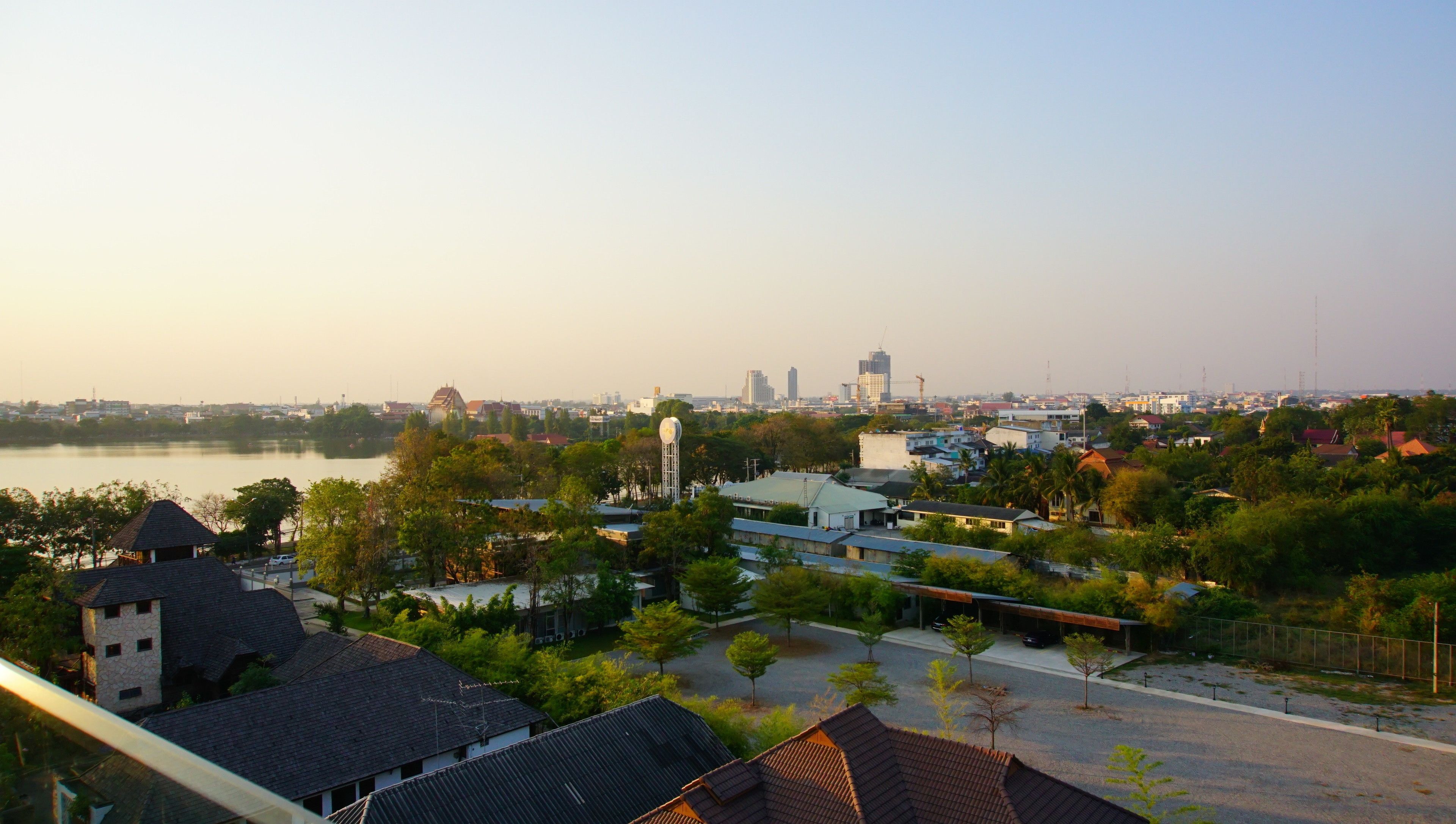 A residential area with houses, a water body, and a distant cityscape with buildings and a tower.