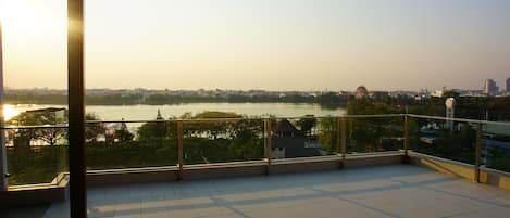 A balcony with a view of a river and cityscape during sunset.
