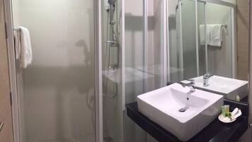 A modern bathroom with a glass-enclosed shower, two sinks, and a large mirror.