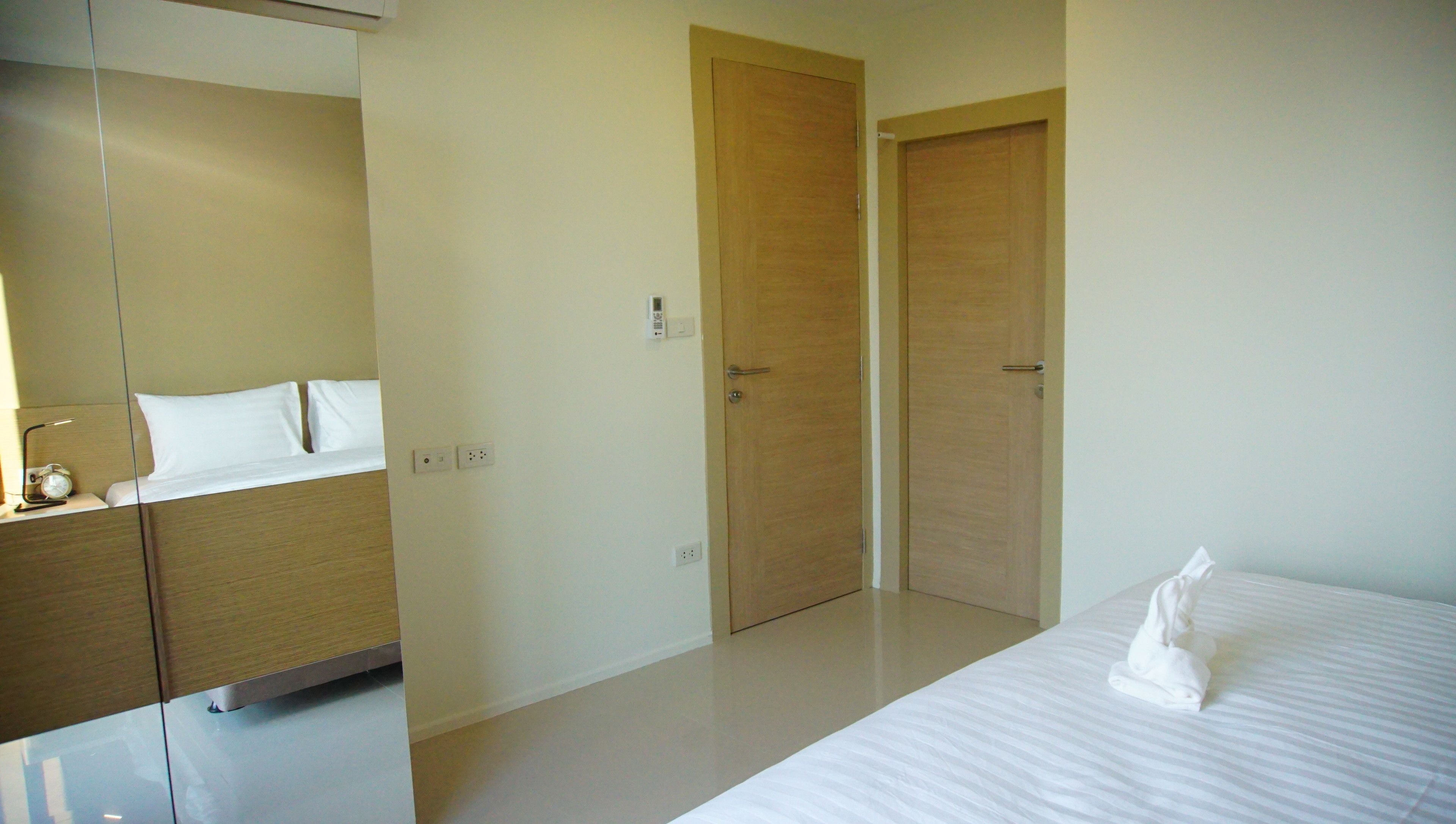 A hotel room with a bed, a nightstand, a mirror, and two wooden doors.