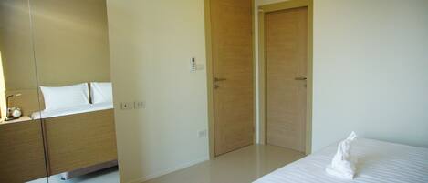 A hotel room with a bed, a nightstand, a mirror, and two wooden doors.