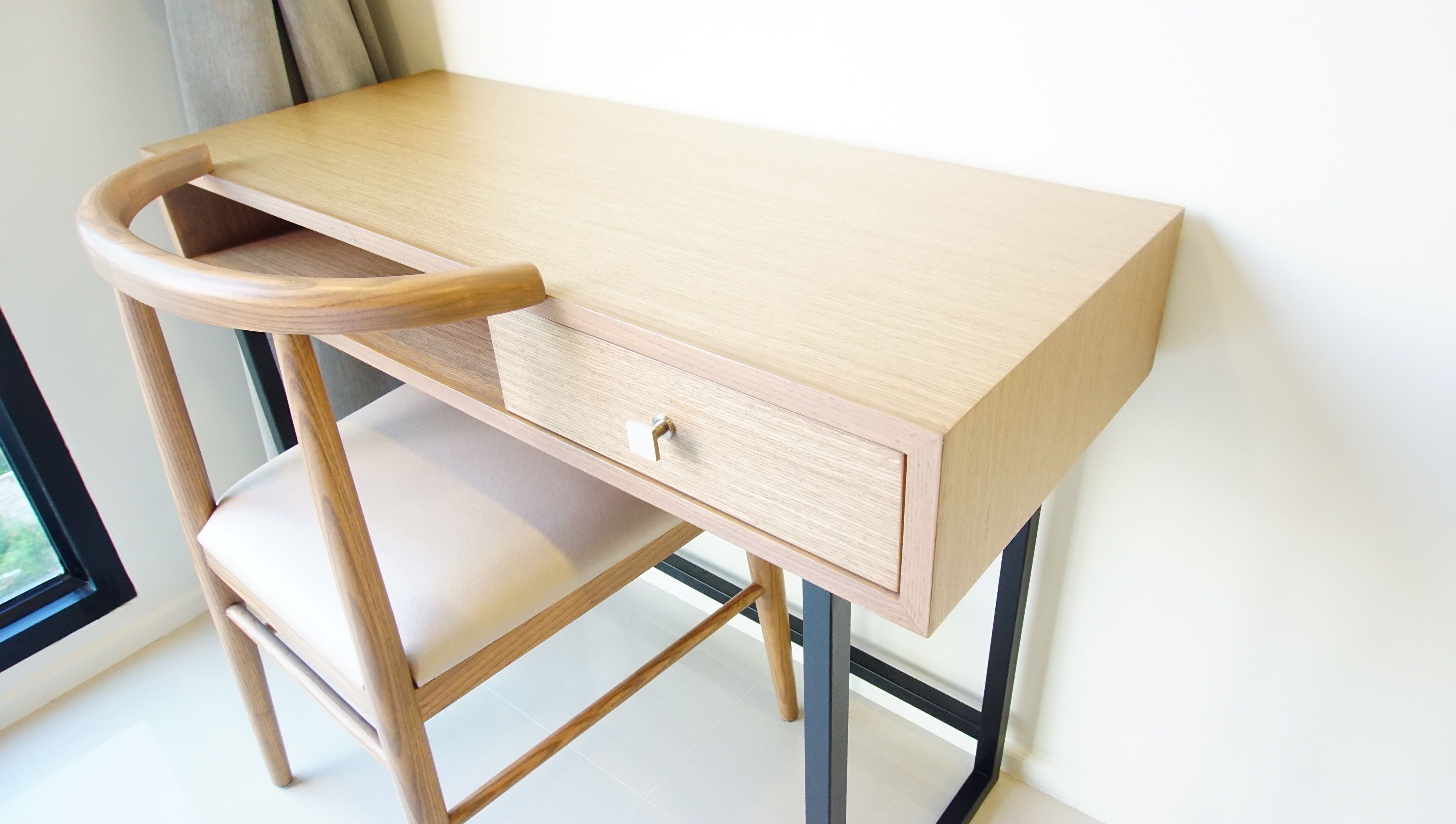 A wooden desk with a drawer and a chair.