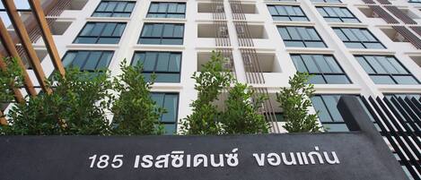 Un edificio moderno con un cartel que indica la dirección, carretera Isanburi 185.