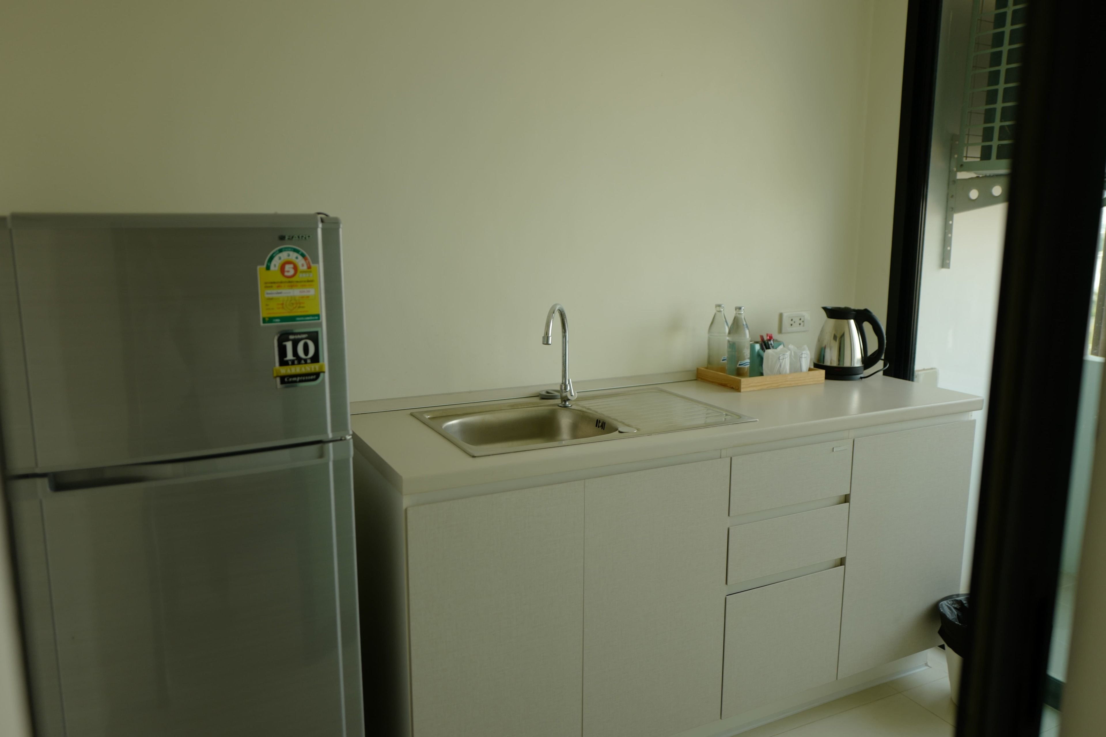 A kitchen with a stainless steel refrigerator, a sink, and a coffee maker on the counter.