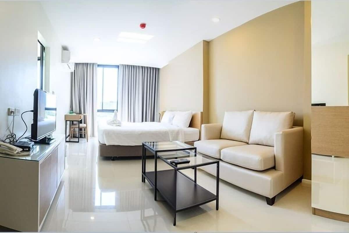 A modern hotel room with a bed, sofa, and a TV on a stand.