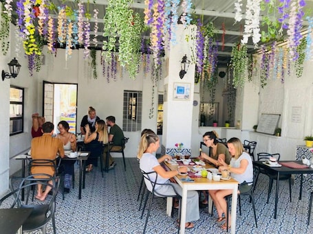 A restaurant with hanging plants, tiled flooring, and patrons dining.
