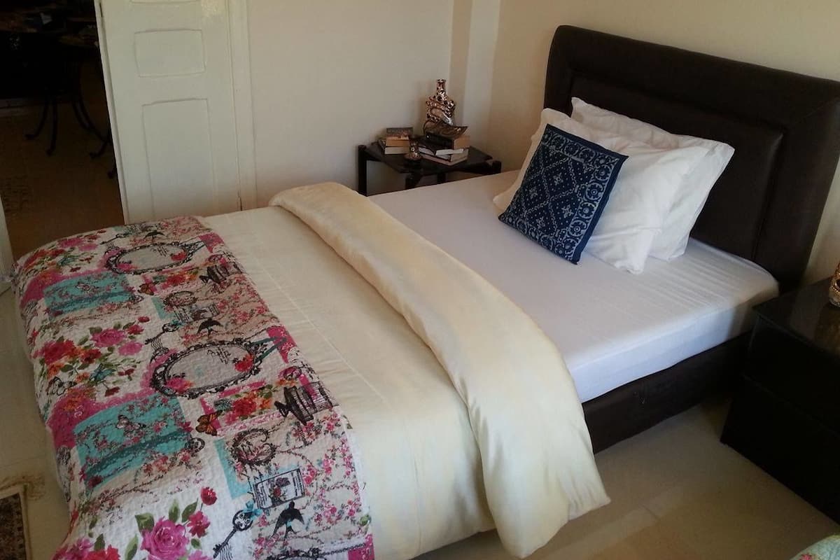A neatly made bed with a floral bedspread and a dark headboard.