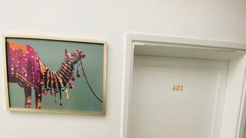 A white door with the number 401 on it, a framed colorful artwork of a camel on the wall, and a marble floor.