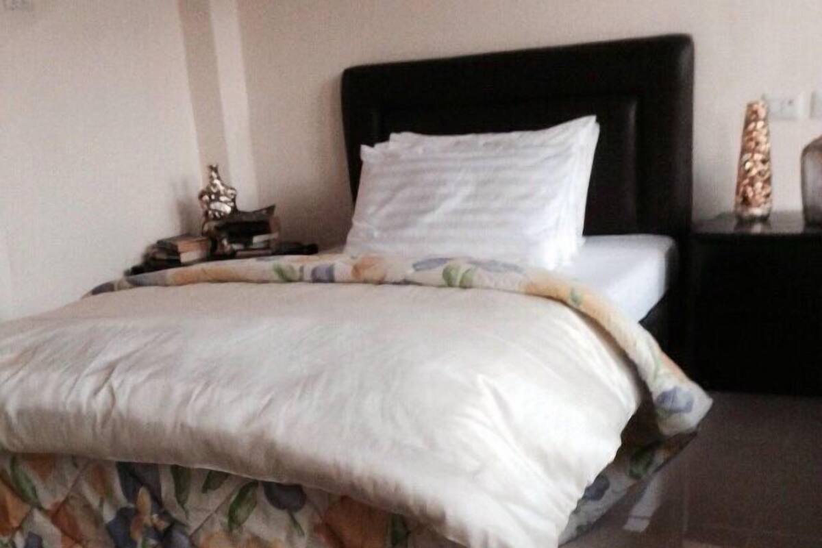 A bedroom with a bed, a nightstand, a lamp, and a rug.