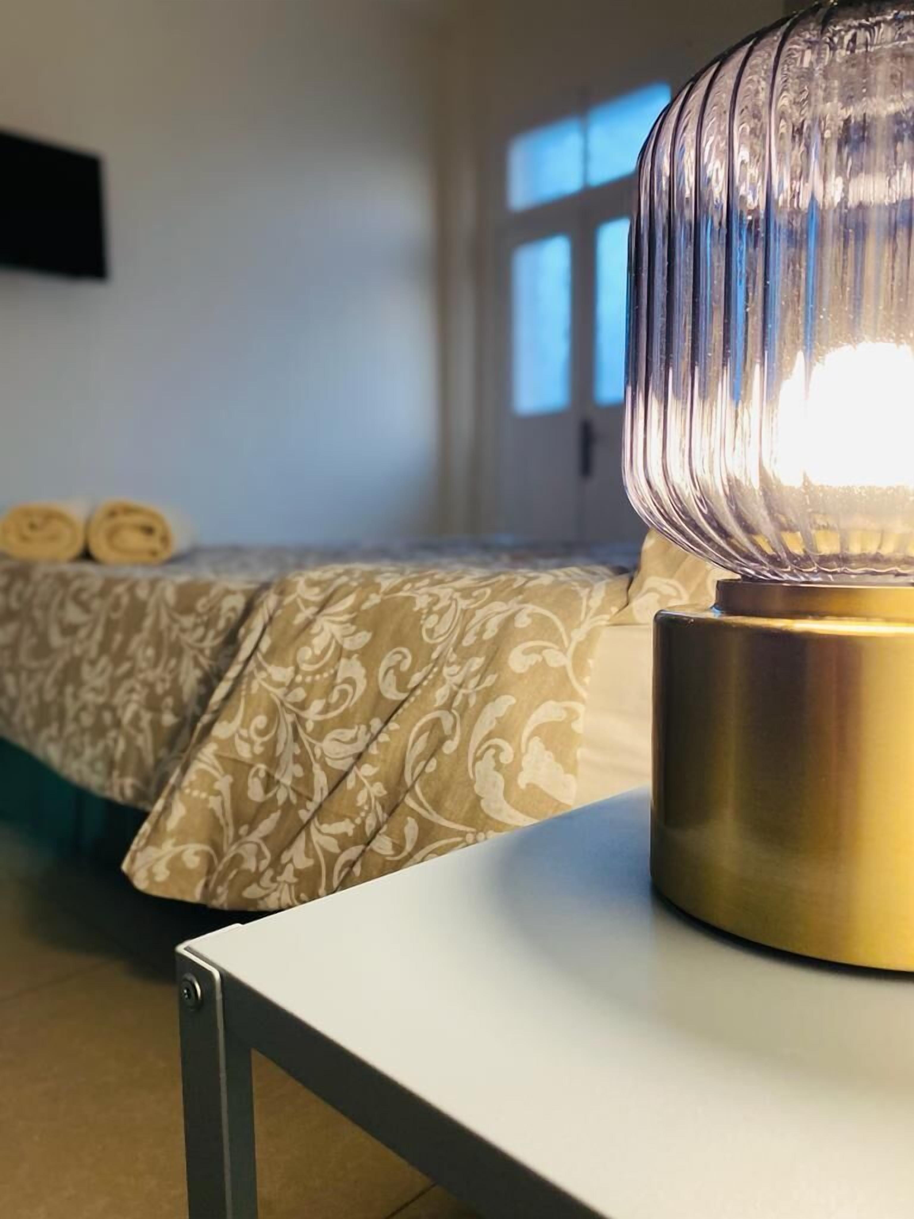 A room with a bed, a bedside table, and a lamp.