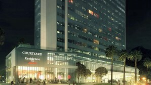 Un hotel Residence Inn Courtyard con fachada de vidrio moderna, varios pisos y una entrada destacada con palmeras y un vestíbulo bien iluminado.