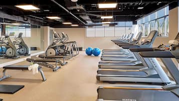 A gym with multiple treadmills, exercise bikes, and a bench.