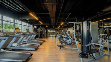 A gym with treadmills, weight machines, and a large window providing natural light.