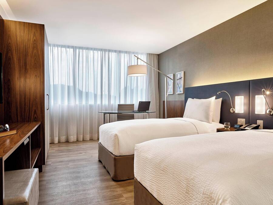 Habitación de hotel con dos camas, un escritorio, una computadora portátil y un televisor.