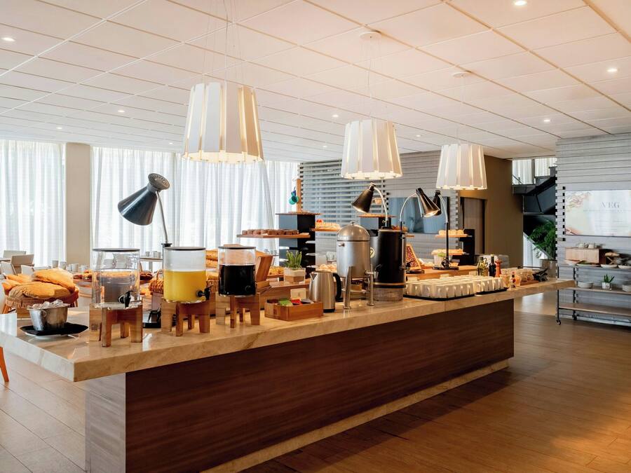 Un espace cuisine moderne doté d’un îlot central, de divers appareils électroménagers et de luminaires suspendus.