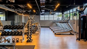 Un gimnasio con cintas de correr, mancuernas, pesas y máquinas de pesas.
