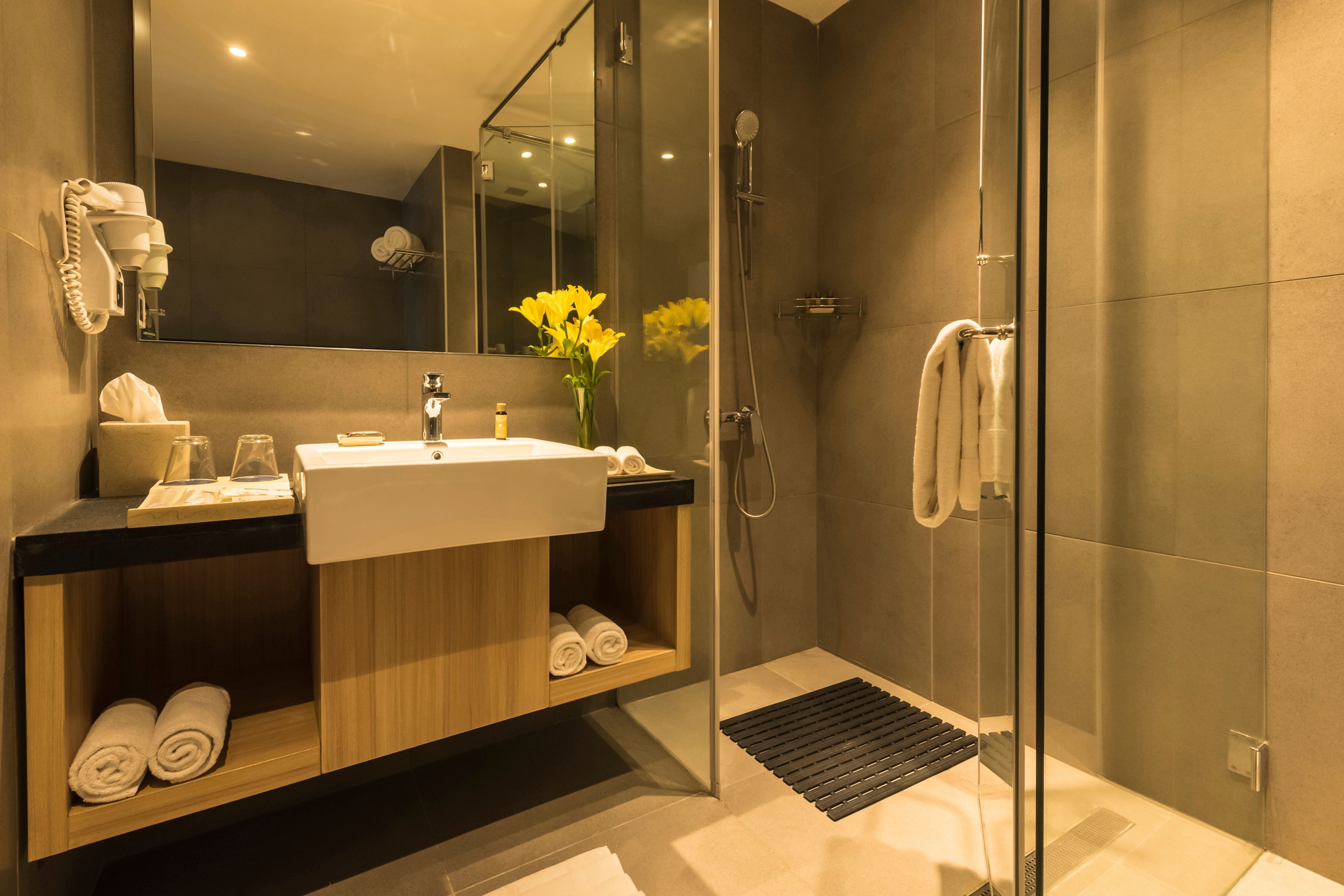 A modern bathroom with a glass shower enclosure, a sink with a mirror above it, and a towel rack with towels.